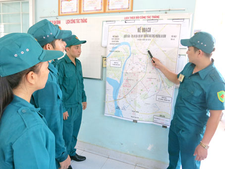 Anh Nguyễn Thanh Sơn (phải) hướng dẫn dân quân thường trực phường An Bình làm quen với sơ đồ tác chiến trị an ở địa phương.