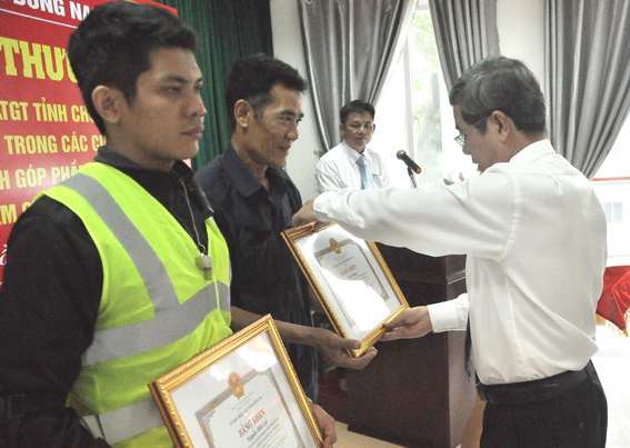  Phó chủ tịch UBND tỉnh Nguyễn Quốc Hùng trao bằng khen cho 2 cá nhân trong việc thành lập các đội tham gia thu gom, làm sạch đinh, vật sắc nhọn trên quốc lộ 51.