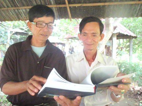 Ông Nguyễn Văn Dương (phải) đang báo cáo các thông tin liên quan đến nhiệm vụ với Chỉ huy trưởng Ban Chỉ huy quân sự xã Long An Phan Duy Tuấn.