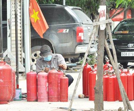 Một nhân viên của cơ sở kinh doanh thiết bị chữa cháy tại phường Tân Hiệp (TP.Biên Hòa) tân trang bình chữa cháy cũ cho khách hàng.