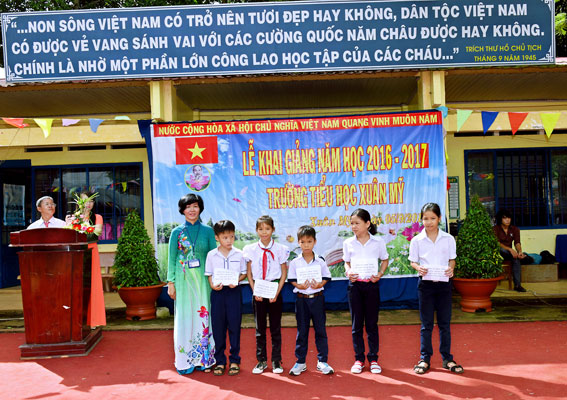 Cô Nguyễn Thị YênTrang, Hiệu trưởng Trường tiểu học Xuân Mỹ trao thẻ bảo hiểm y tế cho học sinh nghèo tại lễ khai giảng năm học 2016-2017.
