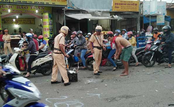 Lực lượng cảnh sát giao thông và người dân thu dọn mảnh kính vỡ tại hiện trường vụ tai nạn.