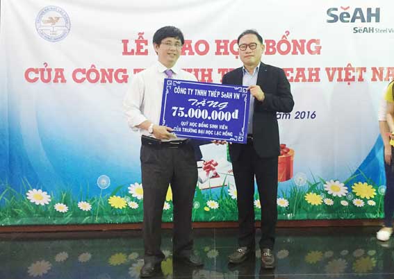 Tổng giám đốc Công ty thép SeAH Vina Nam Hyung Kun trao bảng học bổng tượng trưng 75 triệu đồng cho tiến sĩ Lâm Thành Hiển, Phó hiệu trưởng Trường đại học Lạc Hồng tặng sinh viên (Ảnh: Công Nghĩa)