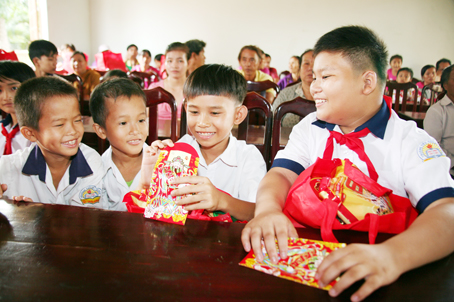 Học sinh nghèo xã Lâm San, huyện Cẩm Mỹ vui mừng bên phần quà tết và phong bao lì xì được nhận nhân dịp Tết Nguyên Đán 2017.