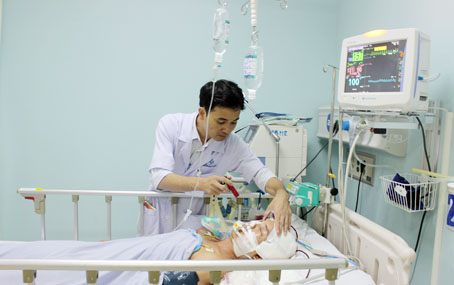 Bác sĩ Nguyễn Xuân Hoàng, phụ trách Khoa Cấp cứu Bệnh viện đa khoa Đồng Nai, khám bệnh cho bệnh nhân L.N.K. bị chấn thương sọ não nặng. Ảnh: Đ.Ngọc