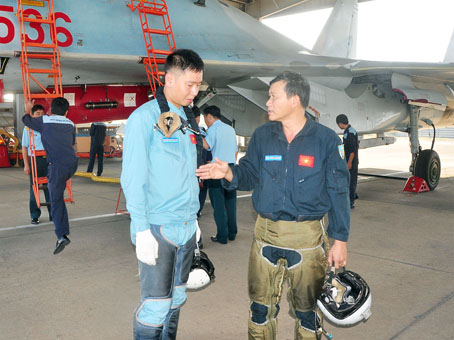 Thượng úy Nguyễn Quang Sáng (trái) lắng nghe phi công đàn anh hướng dẫn sau chuyến bay. Ảnh: Đ.Tùng