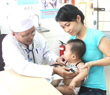 Bác sĩ Lê Văn Giai, Trưởng khoa Nhiễm Bệnh viện nhi đồng Đồng Nai, khám bệnh cho một trẻ bị tay chân miệng. Ảnh: N.Thư