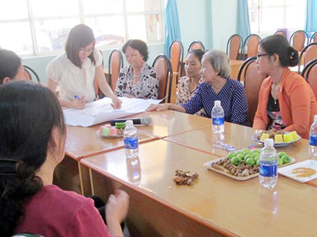 Chị Nguyễn Thị Hiên (đứng phía đầu bàn) chia sẻ với các phụ huynh có con em là người khuyết tật về việc tái hòa nhập cộng đồng.