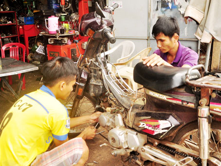 Anh Nguyễn Thành Nghĩa (phải) chăm chỉ trong công việc sửa xe hàng ngày.