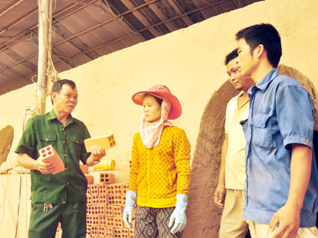 Ông Nguyễn Mạnh Hùng (trái) trao đổi việc sản xuất gạch với nhân công trong xưởng. ảnh: Đ.Tùng