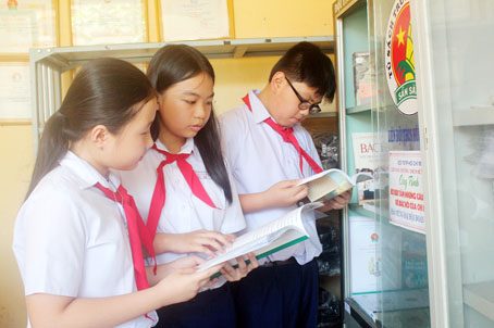 Đội viên Trường THCS Hùng Vương (TP.Biên Hòa) đọc các câu chuyện về Bác Hồ trong giờ ra chơi. Ảnh: N.SƠN