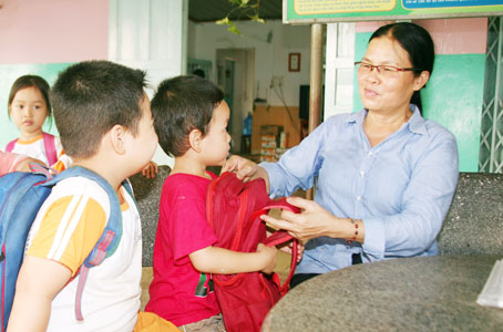 Cô Nguyễn Thị Tuyết (ngụ ấp 2A, xã Xuân Bắc, huyện Xuân Lộc) trao những chiếc cặp do cô vận động được cho học sinh. Ảnh: V.TRUYÊN