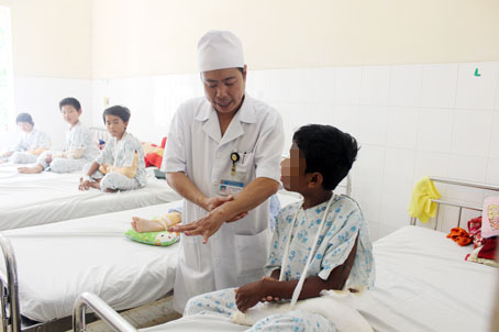 Bác sĩ Phạm Văn Khương, Khoa Ngoại chấn thương - chỉnh hình, bỏng Bệnh viện nhi đồng Đồng Nai khám bệnh cho một bệnh nhân bị té gãy tay. Ảnh: Đ.Ngọc