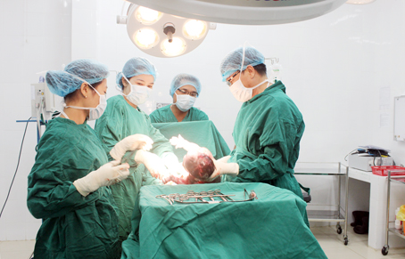 Các bác sĩ Trung tâm y tế huyện Vĩnh Cửu phẫu thuật lấy thai cho một sản phụ sinh khó do có thai lớn. Ảnh: Đ.Ngọc