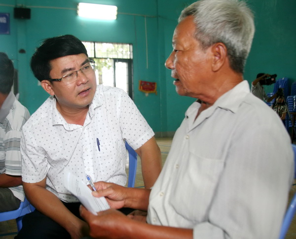 Ông Nguyễn Văn Khang, Phó trưởng Ban Dân vận Tỉnh ủy hướng dẫn người dân xã Phước Tân thể hiện ý kiến qua phiếu khảo sát vào sáng ngày 6-6.