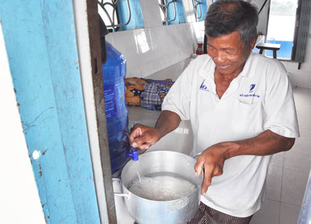 Ông Bùi Văn Dõng lấy nước bình để nấu cơm, phục vụ sinh hoạt hàng ngày.