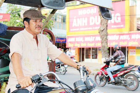 Ông Nguyễn Văn Na trên đường chở hàng về và tìm gốc bằng lăng quen thuộc nơi ngã tư đường để trú nắng, đợi khách.