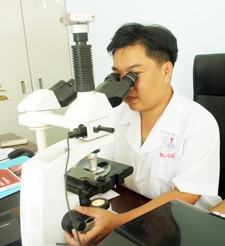 Bác sĩ Nguyễn Gió, Phó giám đốc Trung tâm pháp y Đồng Nai, đang đọc kết quả xét nghiệm vi thể. Ảnh: Đ.Ngọc