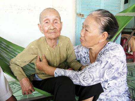 Bà mẹ Việt Nam anh hùng Lê Thị Trơn (trái) được các con cháu quây quần, chăm sóc.