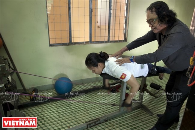  Huấn luyện viên Đổng Quốc Cường hướng dẫn học trò tập thể lực trong phòng tập tạ.