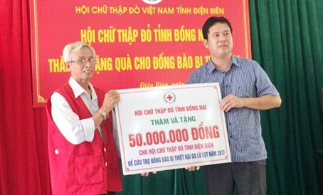 Phó chủ tịch Hội Chữ thập đỏ tỉnh Đồng Nai Nguyễn Văn Xuân (trái) trao bảng tặng 50 triệu đồng ủng hộ đồng bào bị thiên tai ở tỉnh Điện Biên. Ảnh: H.Long