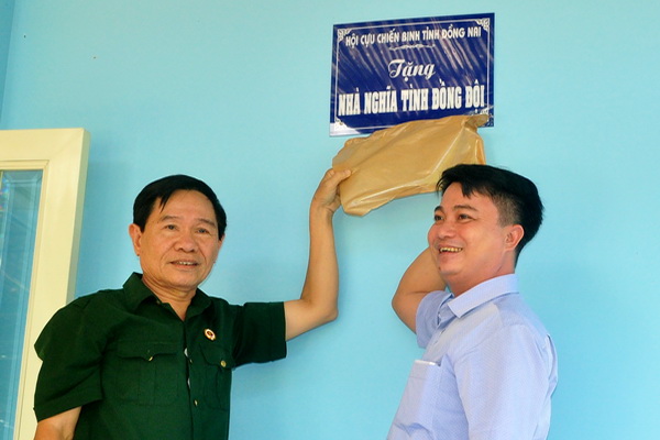 Ông Lê Văn Liên (đứng trái), nguyên phó chủ tịch hội cựu chiến binh tỉnh nhiệm kỳ 2012-2017 và mạnh thường quân Nguyễn Trường Giang mở bảng nhà nghĩa tình đồng đội  (ảnh: Đăng Tùng)
