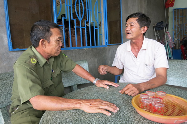 Ông Đinh Công Chúng (phải) đang trao đổi công tác bảo vệ an ninh trật tự với Phó trưởng Công an xã Sông Trầu Vòng A Cẩu.