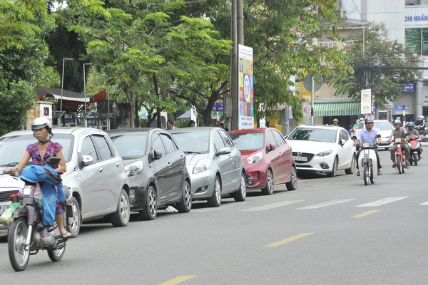 Xe ô tô đậu hàng dài trên đường Hưng Đạo Vương, đoạn gần vòng xoay Biên Hùng, buộc xe máy phải chạy vào làn ô tô.