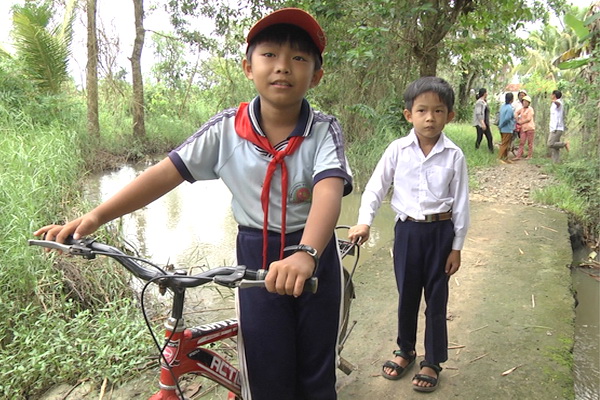 2 cháu Mã Minh Sang và Liều Phi Phi trên đường đi học, băng qua cầu suối Ấp Văn Hóa.