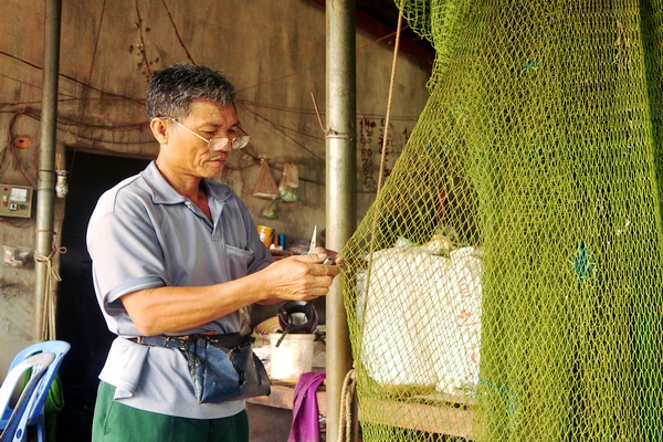 Ông Trần Văn Ngọc tỉ mỉ vá từng mắt lưới bị rách trước khi đem cất, chờ khách đến thuê. Ảnh: Đăng Tùng