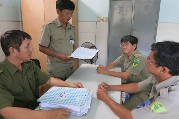 Ông Trần Văn Của (bìa trái) đang nghe Ban bảo vệ dân phố thị trấn Long Thành báo cáo về công tác bảo vệ an ninh trật tự địa bàn.