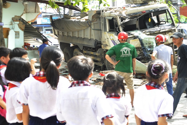  Học sinh Trường tiểu học Nguyễn Tri Phương (phường Hố Nai, TP.Biên Hòa) quan sát xe tải ben sau khi đã đâm sập một phần tường rào và căn-tin của nhà trường.