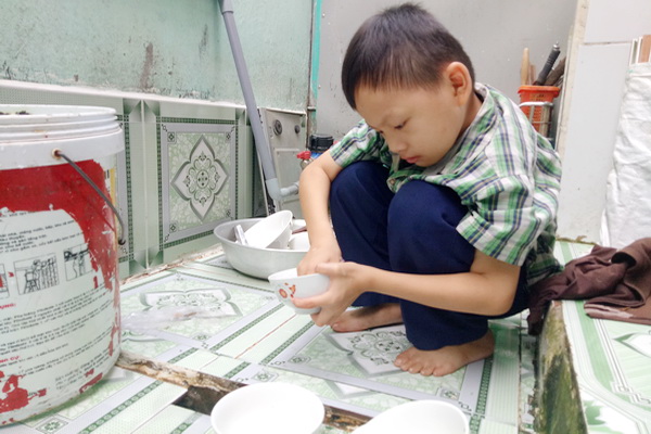 Em Lê Văn Thắng phụ giúp bà ngoại rửa chén.