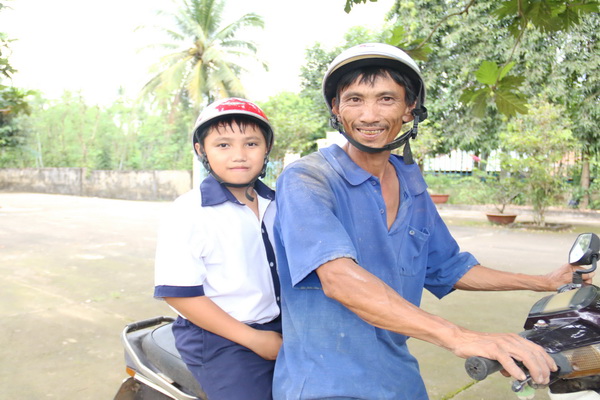 Em Nguyễn Cửu Hưng (học sinh lớp 6 Trường THCS Trà Cổ, xã Trà Cổ, huyện Tân Phú) cùng cha trên đường đi học về.