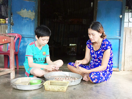 Em Chí Tuấn Kiệt phụ mẹ cạo hạt điều ở nhà.