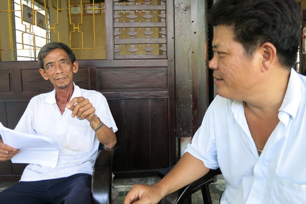 Ông Năm Cho (trái) trao đổi về việc giữ gìn an ninh trật tự ở tổ nhân dân số 18 với Phó trưởng Công an xã Xuân Hòa Lê Hữu Dũng.