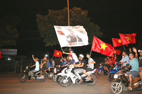 Người hâm mộ diễu hành mang cờ in hình HLV người Hàn Quốc diễu hành trên đường Võ Thị Sáu.