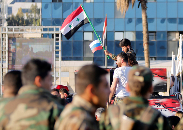 Binh sĩ Syria ở thủ đô Damascus vẫy cờ Nga và Syria vào sáng 14-4 - Ảnh: REUTERS