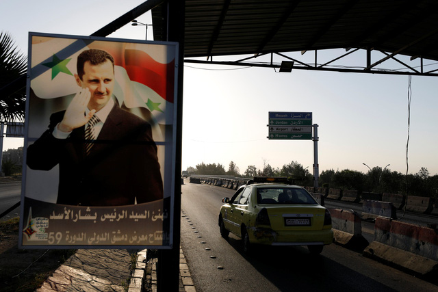 Hình ảnh tổng thống Bashar al-Assad bên con đường chính dẫn vào sân bay ở thủ đô Damascus - Ảnh: REUTERS