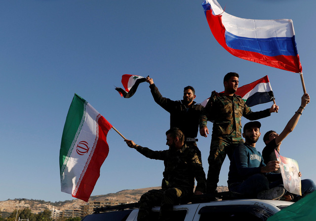 Người dân Syria ở thủ đô Damascus vẫy cờ Syria và cờ Nga sáng 14-4 sau khi đợt không kích của liên quân chấm dứt - Ảnh: REUTERS