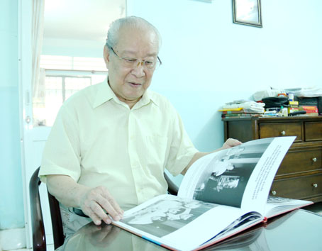 Nhà báo Phạm Minh cùng cuốn sách ảnh của mình. Ảnh: V.TRUYÊN