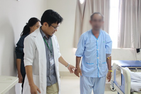 Bác sĩ đang hướng dẫn bệnh nhân T. tập đi lại sau khi được phẫu thuật lấy toàn bộ khối u trong ống sống.