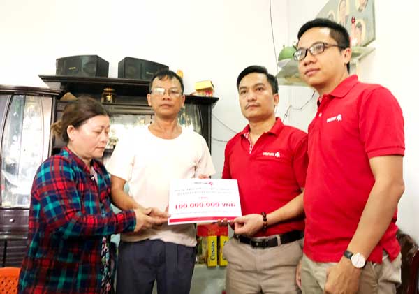 Đại diện Công ty xổ số điện toán Việt Nam (áo đỏ) trao 100 triệu đồng cho gia đình “hiệp sĩ” Nguyễn Hoàng Nam.