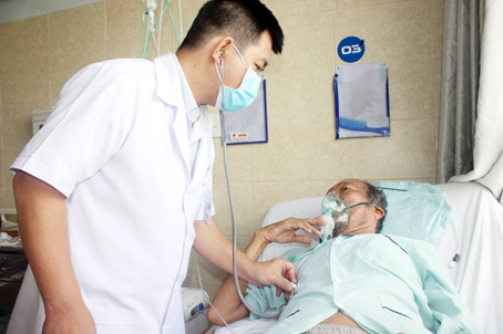 Bác sĩ chuyên khoa I Lê Quốc Khánh, Phó trưởng khoa Hô hấp Bệnh viện đa khoa Đồng Nai, thăm khám cho bệnh nhân N.V.M. Ông M. đang phải thở oxy liên tục do bệnh phổi tắc nghẽn mạn tính. Ảnh: H.DUNG