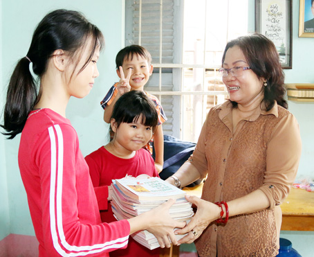 Bà Ngô Thị Bích Hằng, Chi hội trưởng Chi hội phụ nữ ấp Đông Bắc (xã Gia Kiệm, huyện Thống Nhất), trao sách giáo khoa cho học sinh có hoàn cảnh khó khăn.