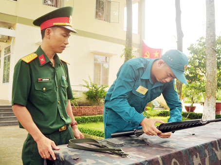 Đại úy Nguyễn Tiến Dũng (trái), trợ lý quân khí, Ban Chỉ huy quân sự huyện Nhơn Trạch, hướng dẫn dân quân cách tháo lắp súng M16. Ảnh: Đăng Tùng
