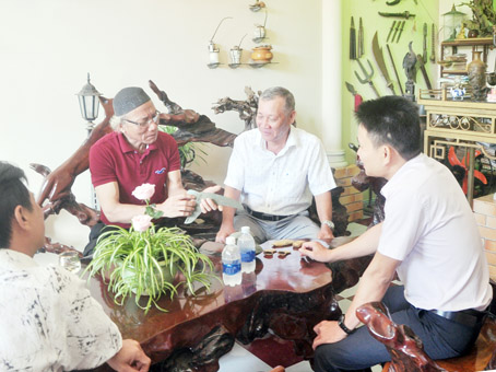 Ông Tô Văn Quý (bìa trái) giới thiệu một vật trong bộ sưu tập đồ xưa của ông với bạn bè.
