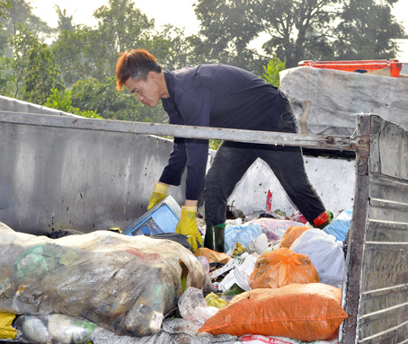 Một người thu gom rác tự do ở TP.Biên Hòa đang phân loại rác.