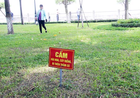 Dù đã có biển cấm nhưng một người phụ nữ vẫn đi lại trên thảm cỏ tại Công viên Nguyễn Văn Trị  (TP.Biên Hòa).