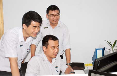 Anh Trần Minh Đức (bìa trái) trao đổi công việc cùng đồng nghiệp. Ảnh: Cẩm Tú